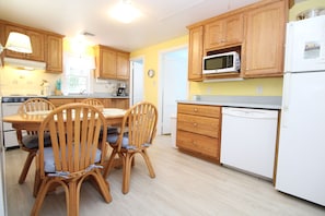 A kitchen with wooden cabinets, a microwave, a dishwasher, and a dining table with chairs.