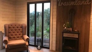 A room with a large window, a tufted armchair, a fireplace, and a wall with the text 'Traumland'.