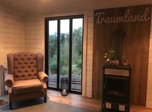 A room with a large window, a tufted armchair, a fireplace, and a wall with the text 'Traumland'.