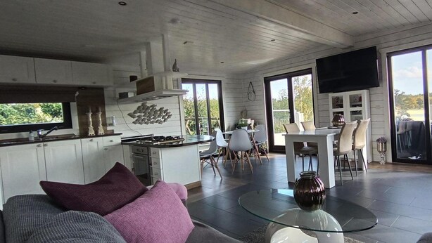 A spacious living area with a kitchen, dining table, and a large window offering a view of the outdoors.