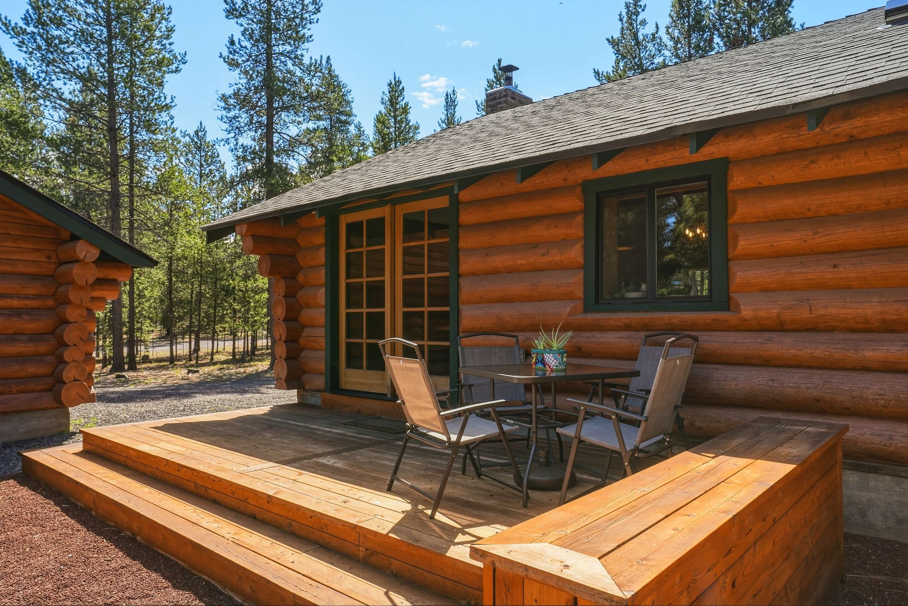 A log cabin with a deck, outdoor seating, and a large window.