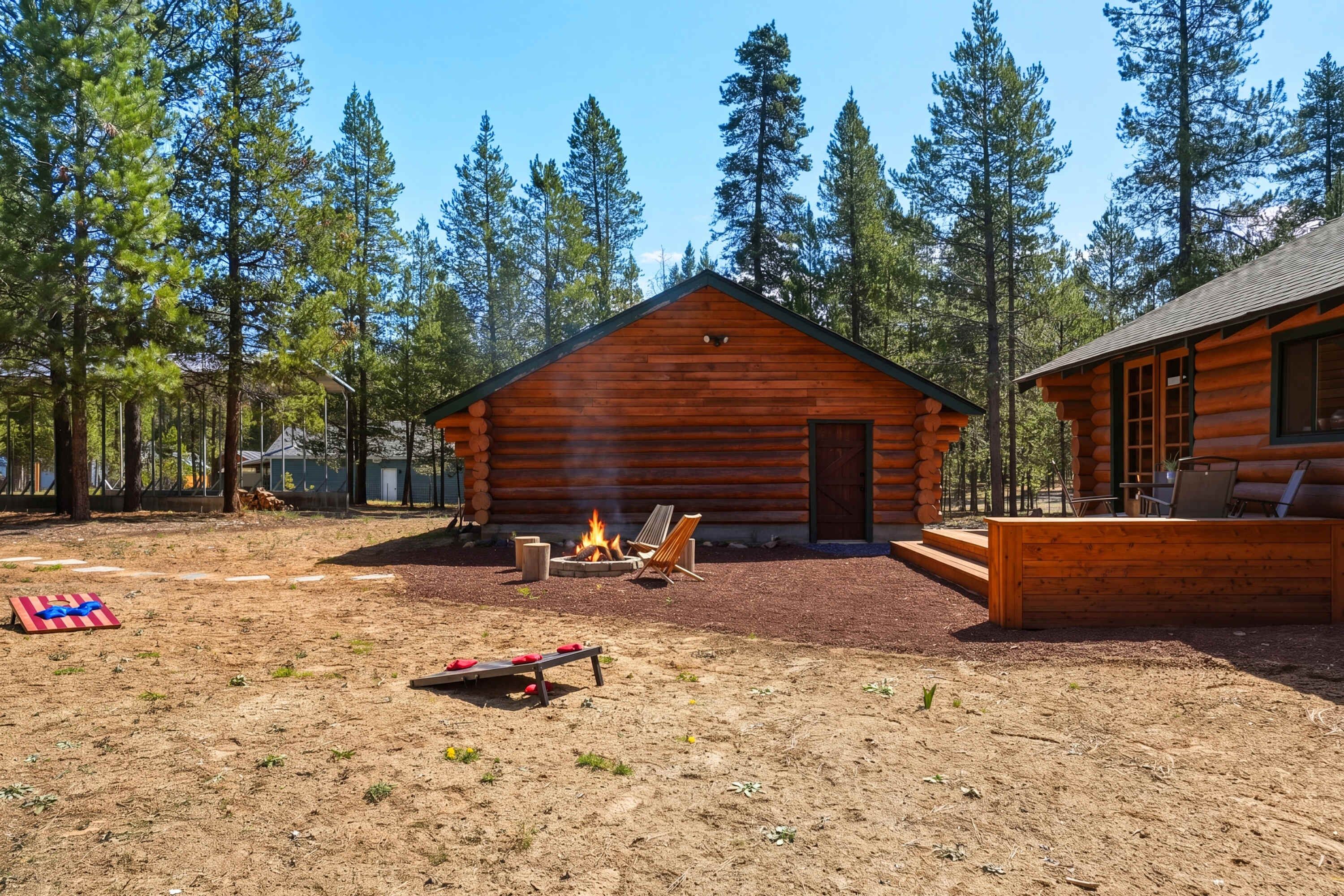A log cabin with a fire pit, outdoor seating, and a view of tall pine trees.