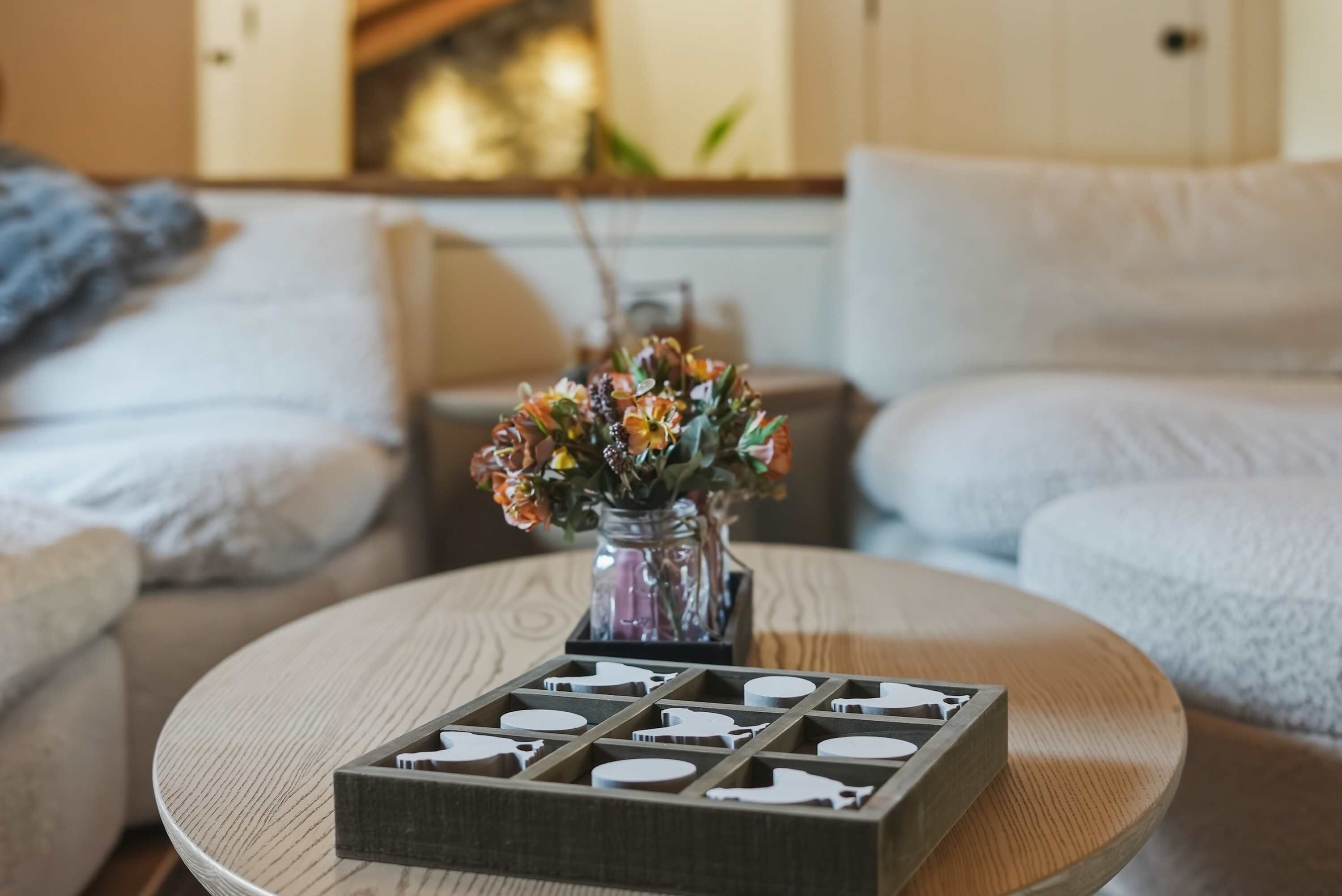 Ett runt träbord med en vas med blommor och en låda med bestick.