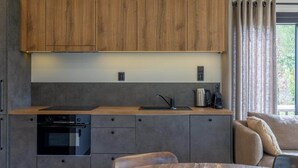 A modern kitchen with wooden cabinets, a built-in oven, and a dining area with a wooden table.