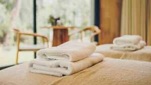 A spa room with two massage tables, each with a folded towel.