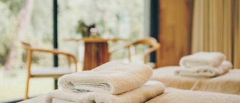 Ein Spa-Raum mit zwei Massagetischen, jeder Tisch mit einem gefalteten Handtuch.