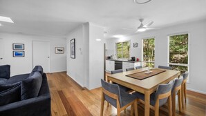 A modern interior with a dining area, kitchen, and living space. - Serene Mount Coolum Escape Near the Beach (Sunshine Coast)
