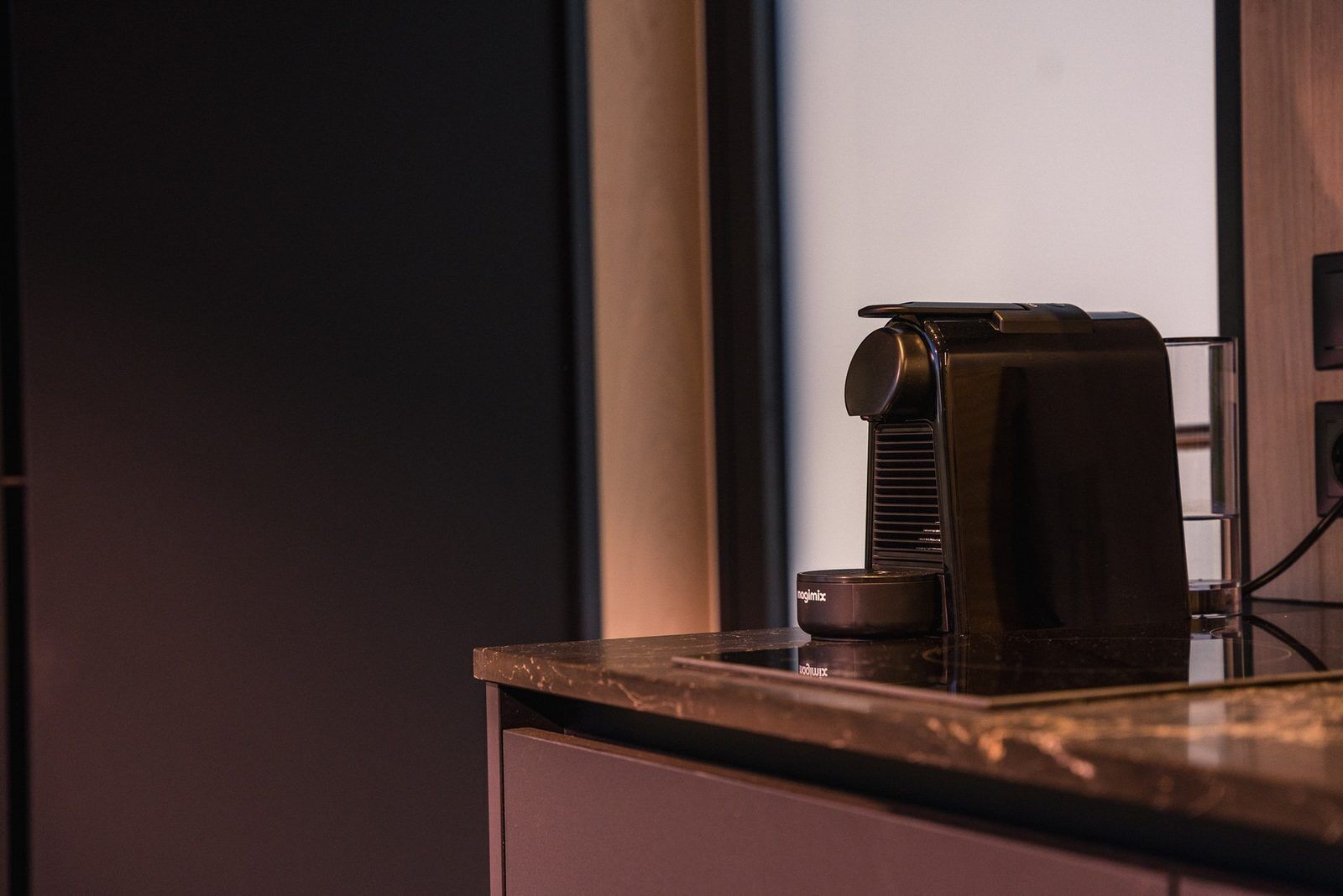 A coffee machine on a countertop with a window in the background.