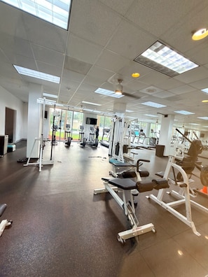 Ein Fitnessstudio mit unterschiedlichen Trainingsgeräten, großen Fenstern und hoher Decke.