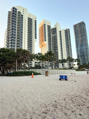 Ein Strandhotel mit Hochhäusern, Palmen und einem Sandstrand.