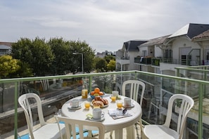 A balcony with a table set for breakfast, including croissants, orange juice, and coffee cups. - Coastal Apartment for Family Stay (Les Sables-d'Olonne)