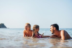 Three people lying on a beach with a calm sea and a distant landmass. - Blue Belle - Walk to Beach, Golf & Cafe`s, slps 7 (Shelley Beach)