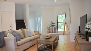 A living room with a sofa, coffee table, and a TV. - Blue Belle - Walk to Beach, Golf & Cafe`s, slps 7 (Shelley Beach)