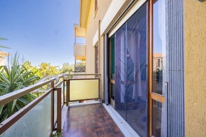 A balcony with a metal railing, a sliding glass door, and a view of the surrounding greenery. - Il Giardino by Wonderful Italy (Sanremo)