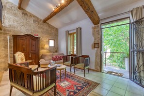 Un interno rustico con pareti in pietra a vista, arredi in legno e un balcone con cancellata in ferro battuto.