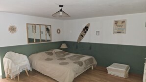A bedroom with a bed, a chair, a table, a hanging surfboard, a mirror, and wall decorations. - Provencal village between Aix en Provence and Cassis (Fuveau)