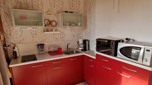 A compact kitchen with red cabinets, a microwave, a toaster, and a coffee maker.