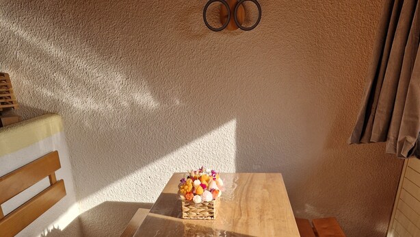 A wooden table with a woven basket and flowers, a bench, and a wooden floor.