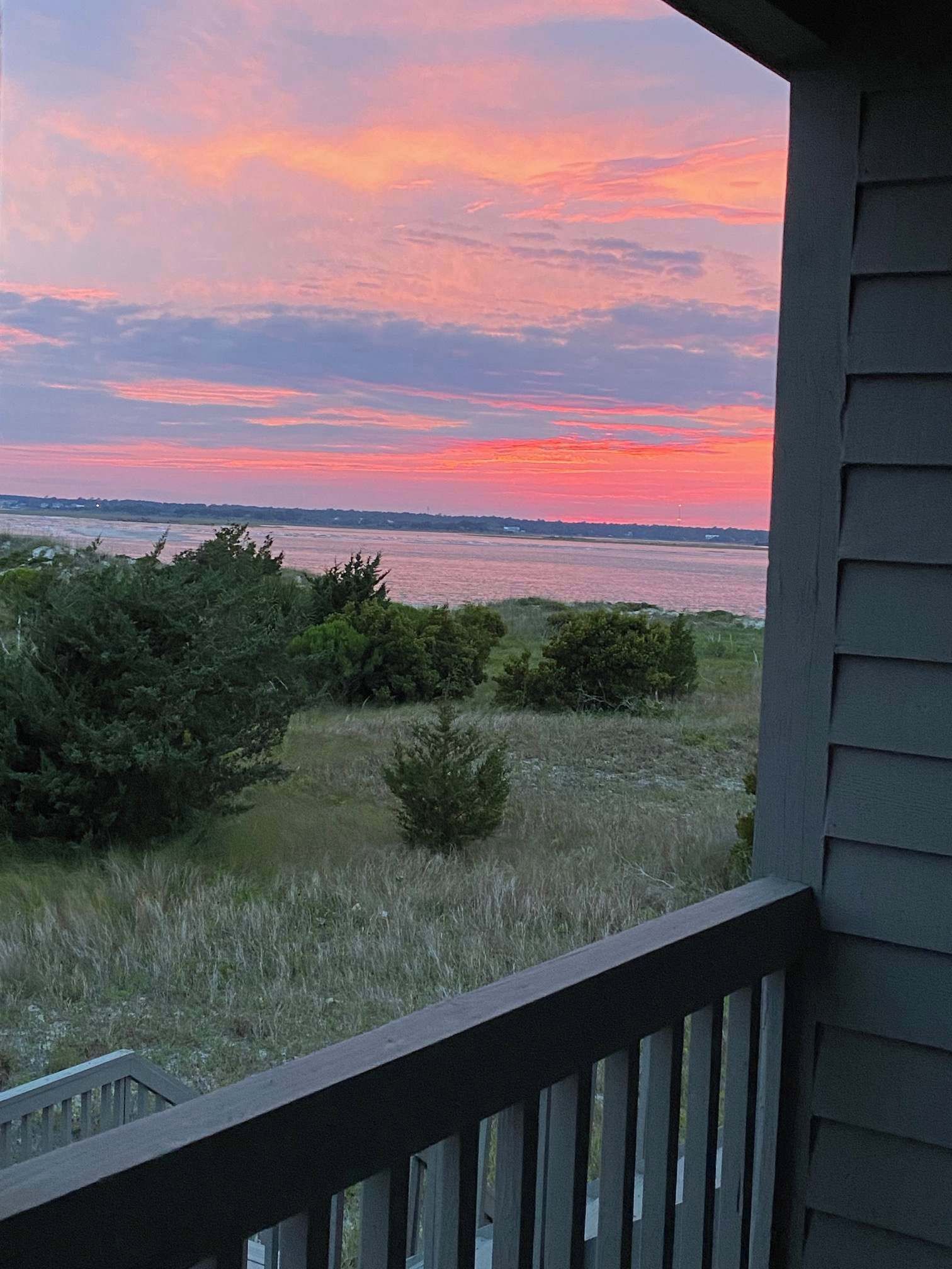 Blick vom Balkon auf ein Gewässer bei Sonnenuntergang.