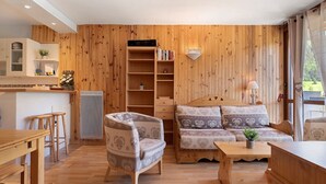 A wooden-paneled room with a sofa, a chair, a table, and a bookshelf. - Superb Apartment with Mountain View at the Foot of the Slopes (Villard-de-Lans)