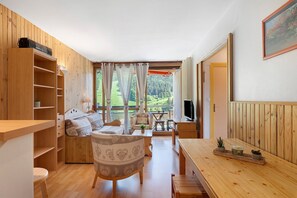 A wooden interior with a sofa, TV, and dining area.