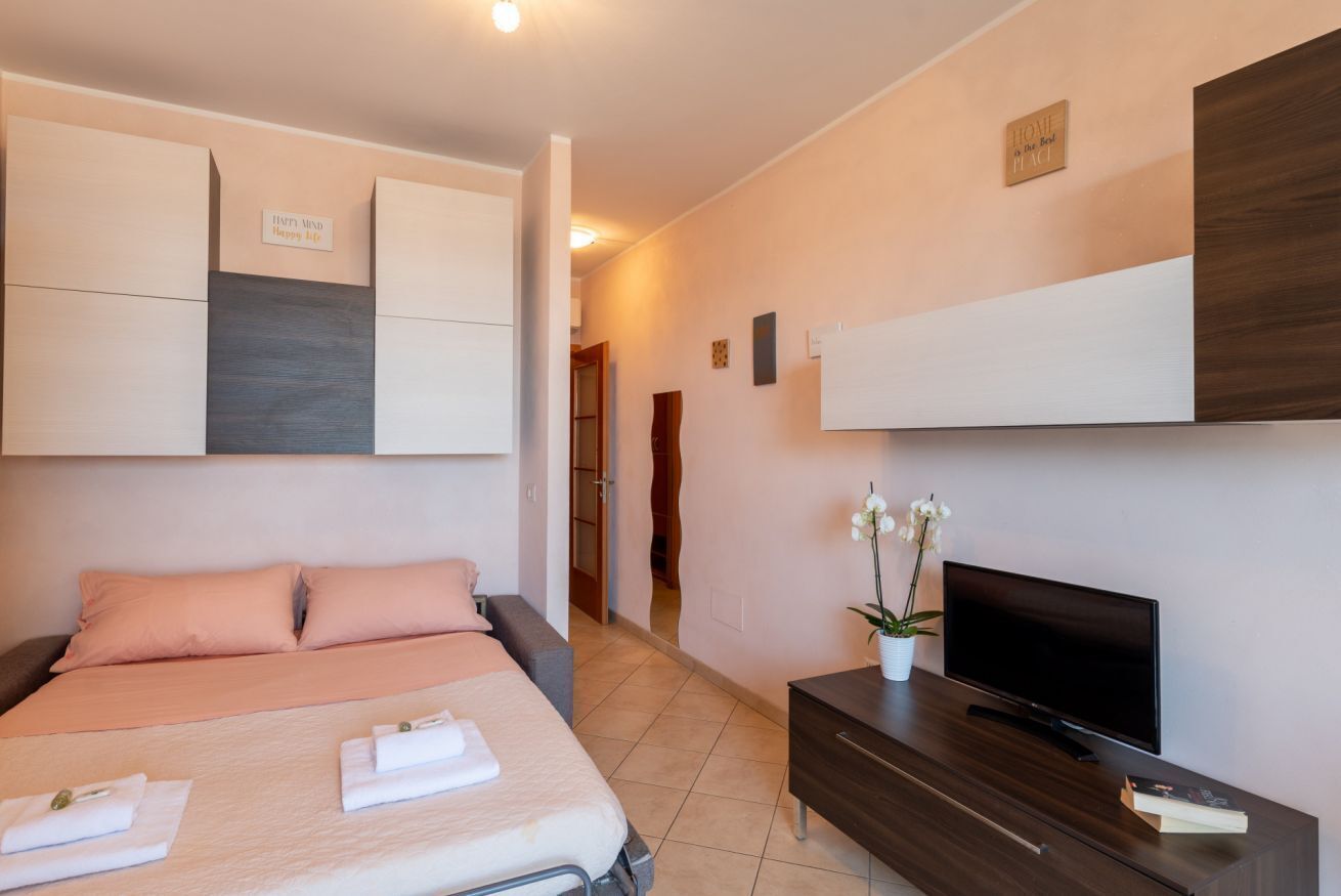 Una habitación de hotel con una cama, televisión, cómoda y mueble de pared.
