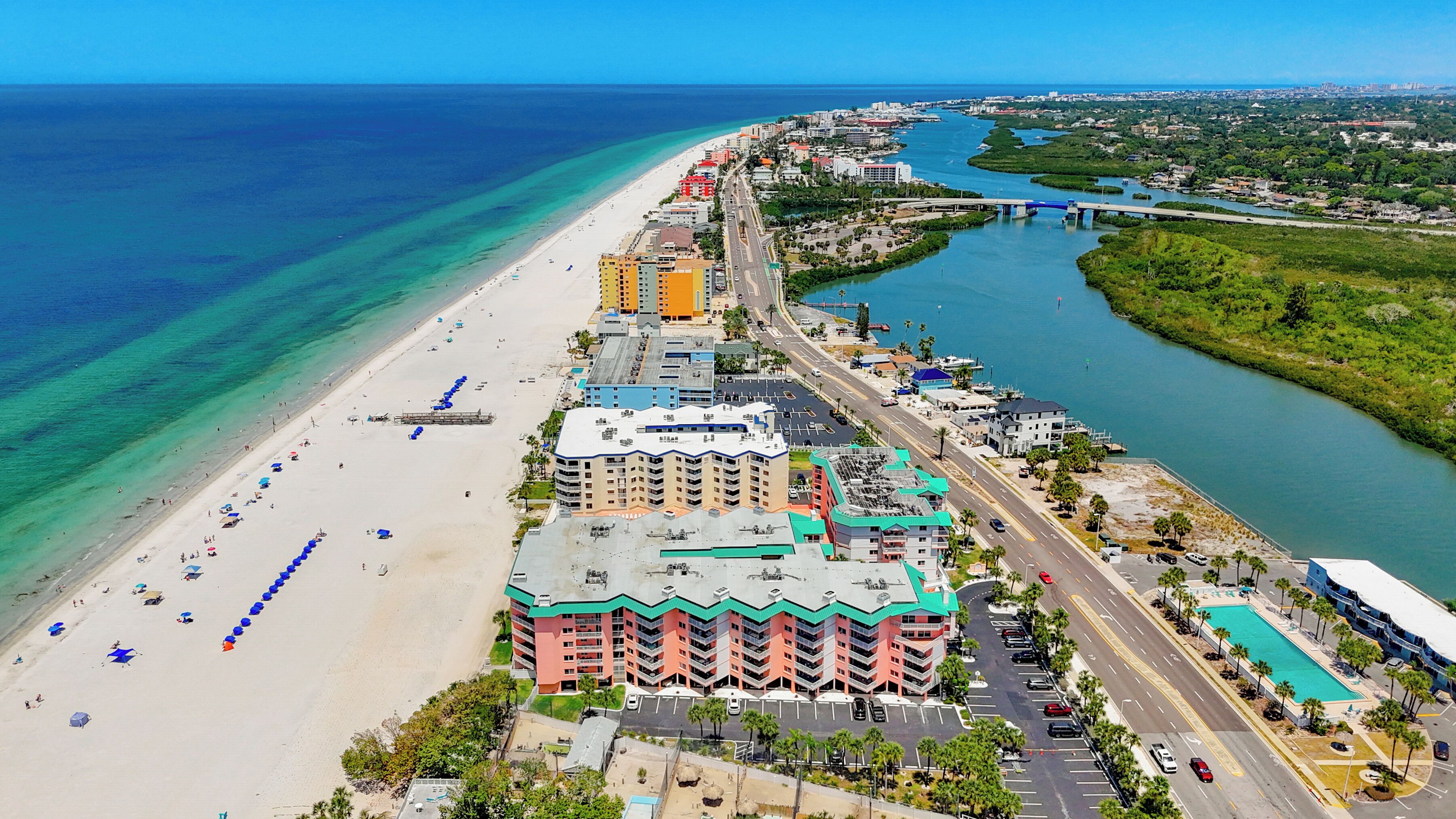 Ein Küstenhotel mit Blick auf den Strand, mehreren Parkebenen und einem Hafen.