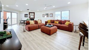 Ein geräumiges Wohnzimmer mit einer Eckcouch, einem Couchtisch und einem Essbereich mit Tisch und Stühlen.