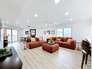 Ein geräumiges Wohnzimmer mit einer Eckcouch, einem Couchtisch und einem Essbereich mit Tisch und Stühlen.