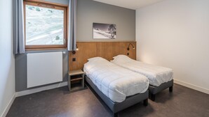 A bedroom with two beds, a window with curtains, a radiator, a picture on the wall, and a ceiling light. - 6-guest Alpine Rental With Balcony (Auris)