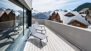 A balcony with a view of snow-capped mountains, wooden buildings, and a clear sky. - 6-guest Alpine Rental With Balcony (Auris)