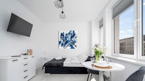 Habitación de hotel moderna con cama, escritorio, silla, televisión y ventana con vistas a la ciudad.