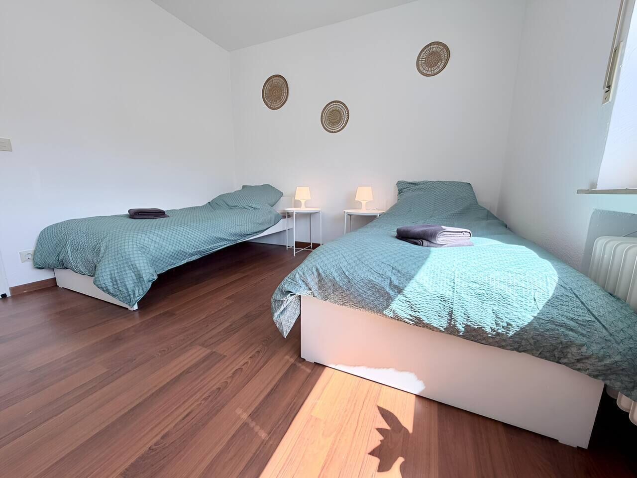 Un dormitorio con dos camas, techo blanco y radiador.
