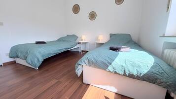 Un dormitorio con dos camas, techo blanco y radiador.