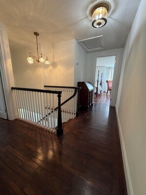 A wooden staircase with a white railing, a chandelier, and a wooden bench.