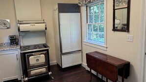 Una cucina con fornello, frigorifero e una finestra vista alberi.