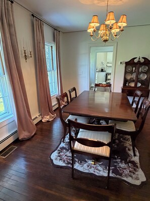 A dining room with a wooden table, chairs, a chandelier, and a patterned rug. - Fabulous 4 bedroom 4 bath home in charming Portsmouth RI Steps from Newport Polo (Portsmouth)