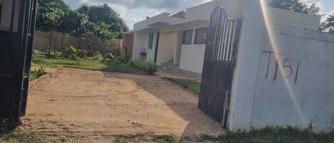 A gated residential area with a paved entrance and a building with a white exterior.