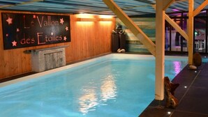 Una piscina interior con techo de madera y un cartel que dice 'Le Vallon des Etoiles'.