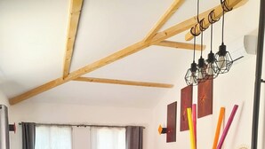 Una cocina moderna con comedor, vigas de madera y una lámpara colgante.