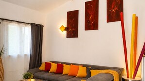 Una sala de estar con un sofá gris, una mesa de centro redonda, un tapete tejido y un techo de madera.