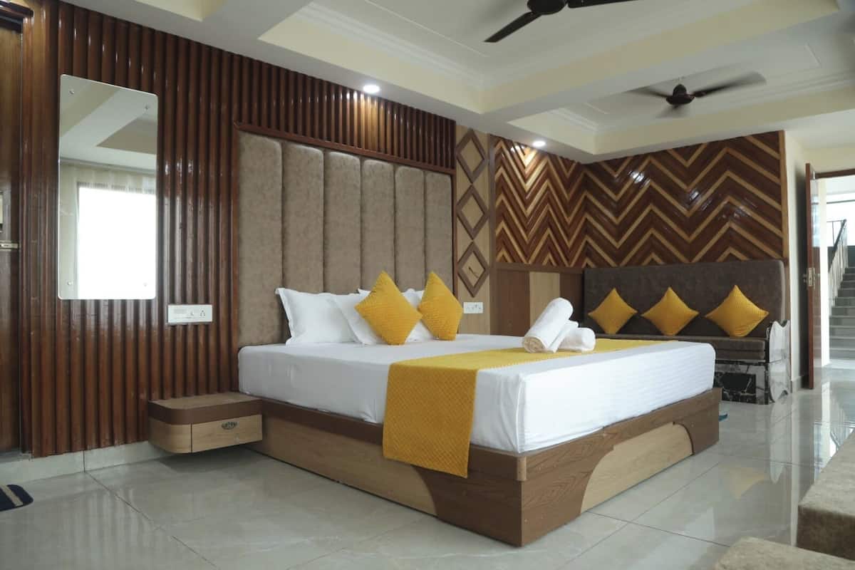 A hotel room with a large bed, a ceiling fan, and a herringbone-patterned wall.