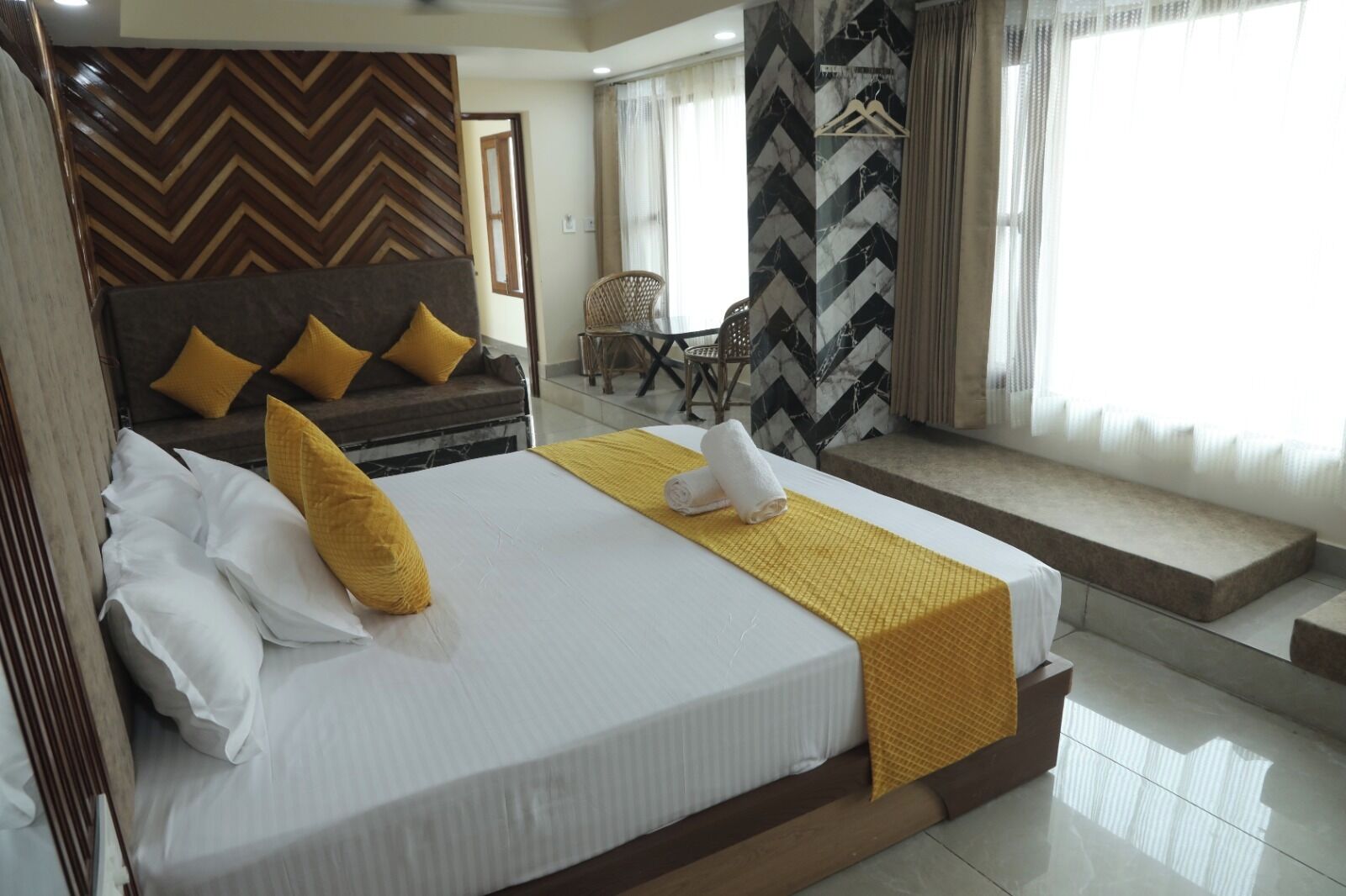 Una habitación de hotel con cama, sofá, sillón y vistas al exterior.