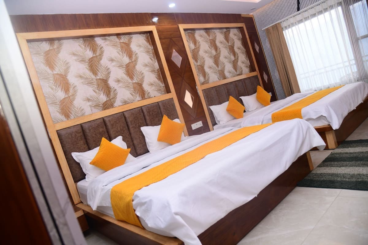 A hotel room with two beds, wooden headboards, and a patterned wall.