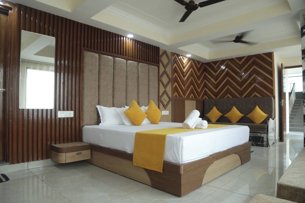 A modern hotel room with a large bed, a ceiling fan, and a herringbone-patterned wall.