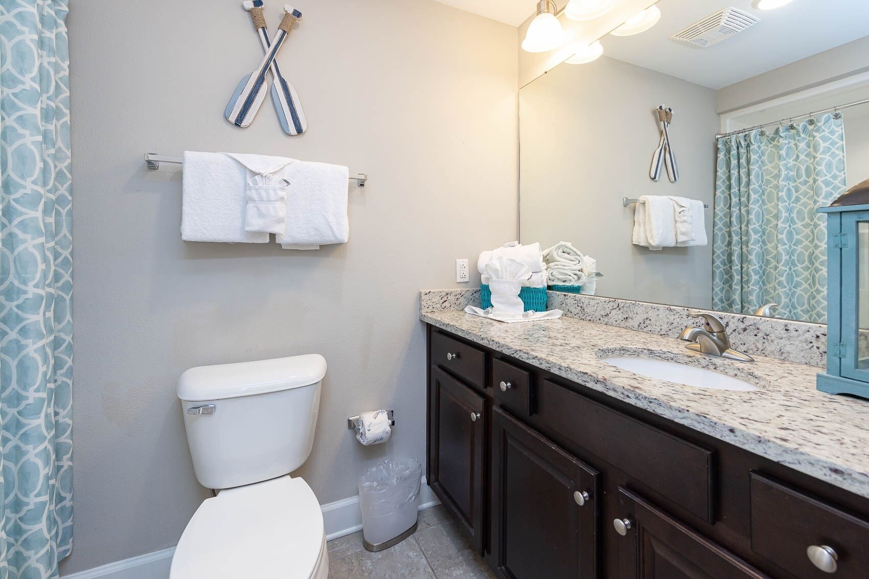 A bathroom with a toilet, a sink with a mirror, and towels on a rack.