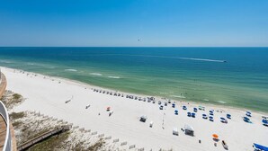 Ein Strand mit Reihen von Sonnenschirmen und Liegestühlen, einer Holzpromenade und freiem Blick auf das Meer.
