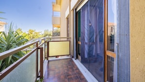 A balcony with a metal railing, a sliding glass door, and a view of the surrounding greenery. - Il Giardino by Wonderful Italy (Sanremo)
