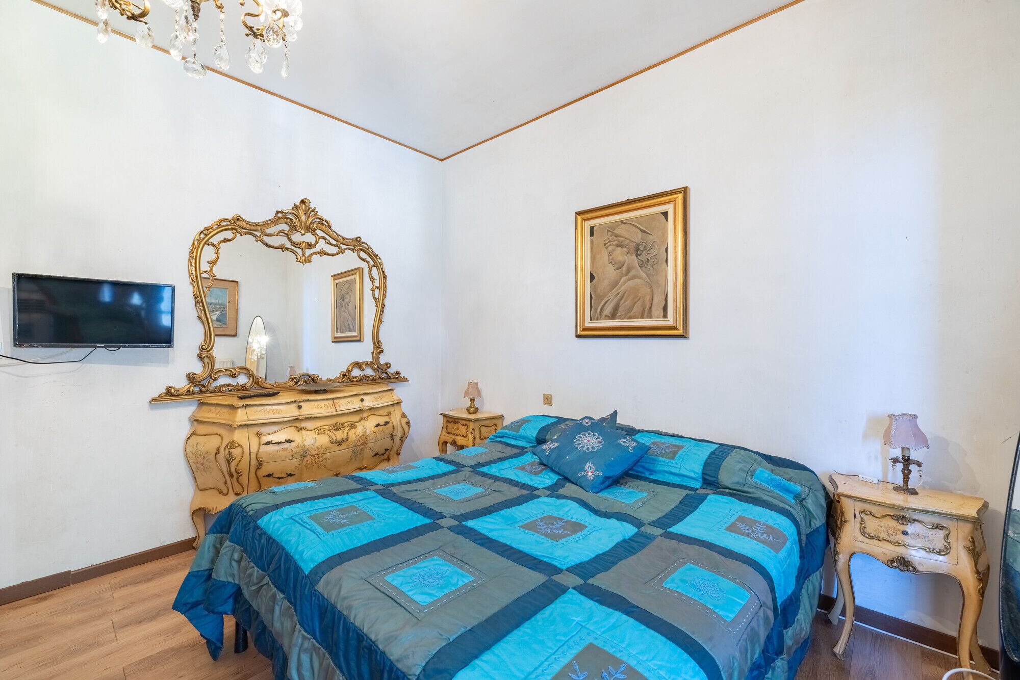 Une chambre à coucher comprenant un lit, une commode, une coiffeuse et un téléviseur.
