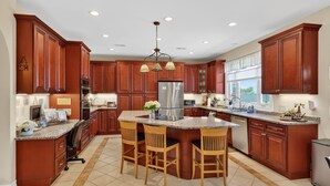A kitchen with wooden cabinets, a central island with bar stools, stainless steel appliances, and pendant lighting. - Milford Quiet Coastal Retreat 3br Sleeps 8 3 Bedroom Home (Milford)